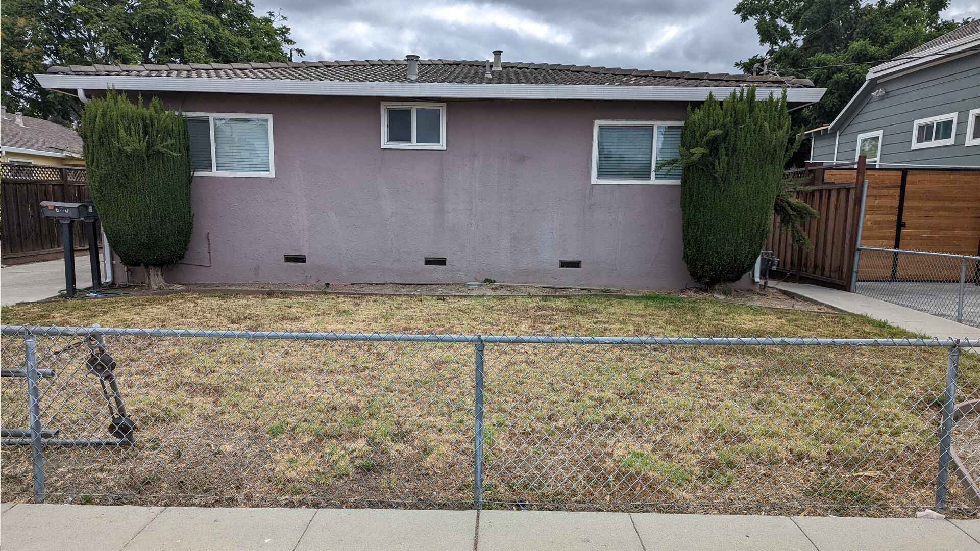 Not-Renovated Barren Front Yard with Dirt and an Old Chain-Link Fence